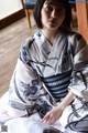 A woman in a blue and white kimono sitting on a bed.