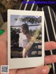 A person holding up a polaroid photo of a little girl.