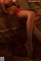 A woman in fishnet stockings sitting on a bed.