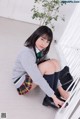 A young woman in a school uniform is sitting on the stairs.