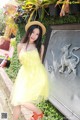 A woman in a yellow dress and straw hat posing for a picture.