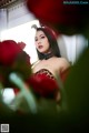 A woman in a leopard print dress sitting in front of red roses.