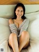 A woman sitting on a bed smiling at the camera.