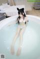 A woman in a white bikini sitting in a bathtub.