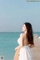 A woman in a white dress standing on a wooden pier.