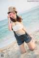 A woman in a straw hat and overalls on the beach.