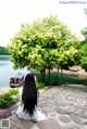 A woman sitting on a stone walkway next to a body of water.