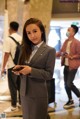 A woman in a gray suit standing in an airport.