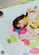 A woman laying in a bathtub surrounded by balloons.